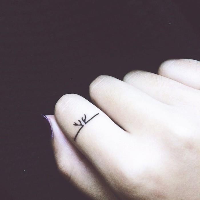 Un piccolo tattoo sull'indice di una donna con inchiostro di colore nero