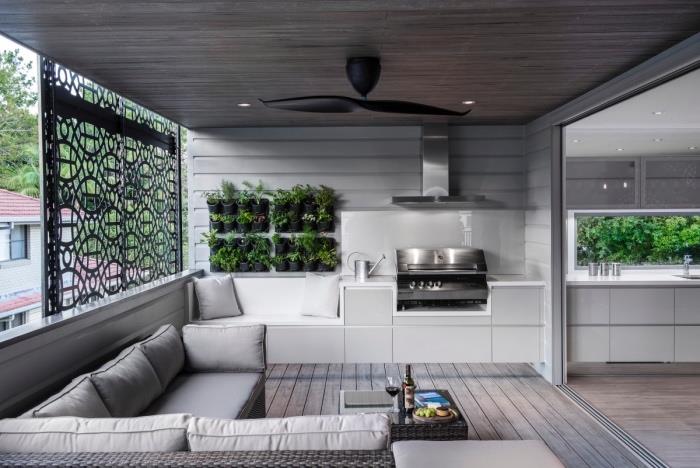 passa in ett litet vitt kök, med dammsugare i rostfritt stål, parkettgolv och grå soffa med en grön växtvägg för en zen -touch, rotting soffbord
