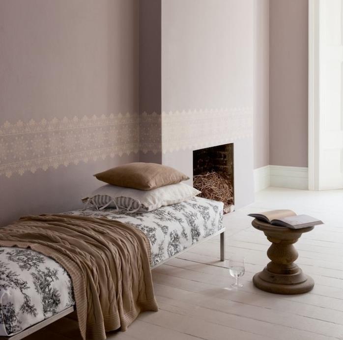 طلاء رمادي داكن فاتح في غرفة معيشة أنيقة مع مدفأة ، كرسي صالة يغطي أبيض مع أنماط رمادية ، بطانية ووسائد رمادية اللون ، كرسي خشبي