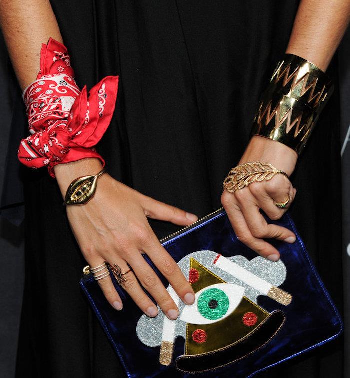 ženské predlaktie a ruky s doplnkami a šperkami vrátane červenej šatky pripevnenej na zápästí ako náramok