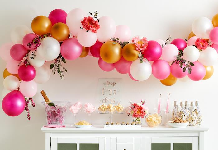 båge av vita, guld och rosa ballonger ovanför en vit buffé med godis sockervadd, po majs, cirkusfest tema