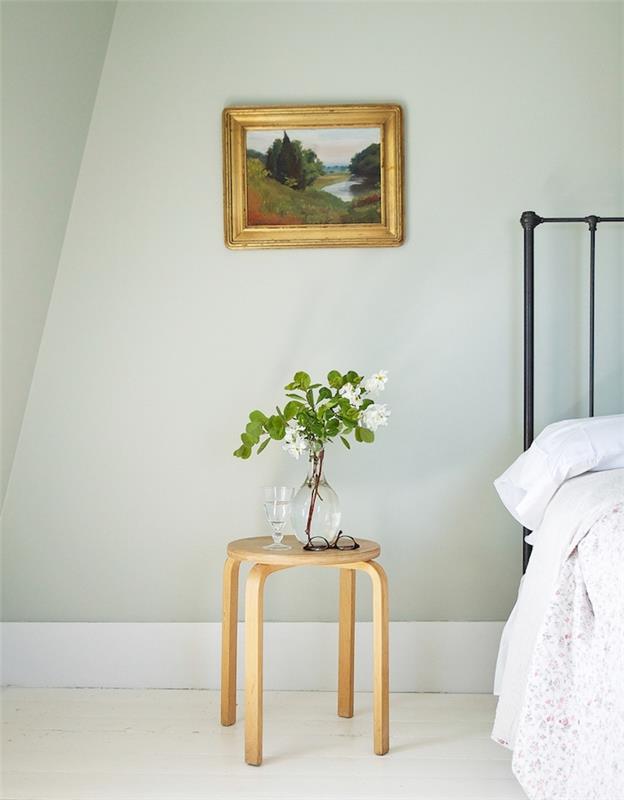 dekor spálne pre dospelých, šedozelené steny, vintage čierna kovová posteľ, sivobiela podlahová krytina, drevený nočný stolík, minimalistický štýl