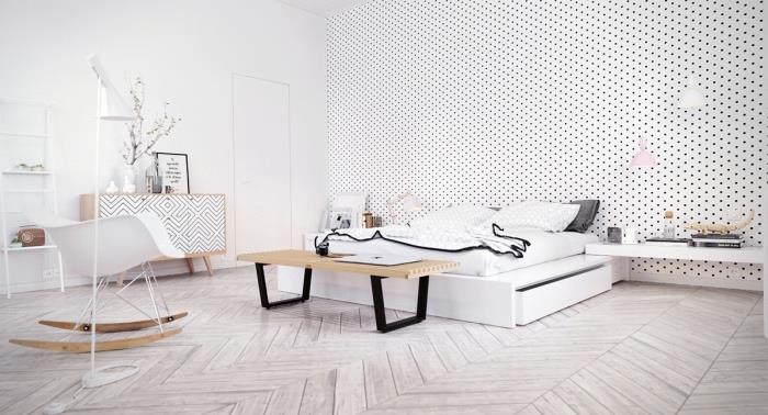 Dekor v škandinávskom štýle, svetlé parkety, biela posteľ a biela, čierna, sivá posteľná bielizeň, biela akcentovaná stena s bodkami, škandinávska komoda, hojdacie kreslo