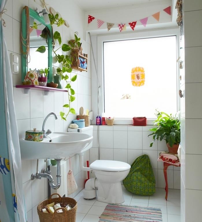 malá dekorácia do kúpeľne s retro bielymi dlaždicami, bielym umývadlom a WC, ozdobnou girlandou, farebnými rastlinami a doplnkami