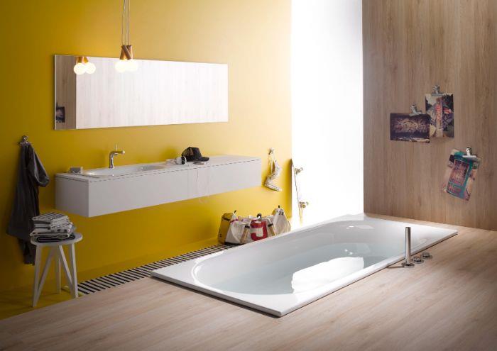 žltá farba na stenu do kúpelne s obdĺžnikovým zrkadlom a bielou skrinkou, drevená podlahová krytina, vaňa zabudovaná do podlahy
