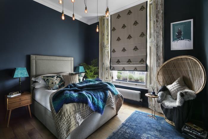 farba spálne pre dospelých tmavomodrá, šedá posteľ s prikrývkou z kačacej modrej, kreslo v orientálnom dizajne, drevený nočný stolík