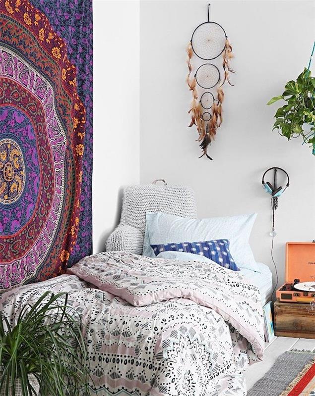 Dekorácia steny v spálni, obrovský lapač snov vyrobený zo štyroch obručí rôznych veľkostí, hnedé perie, posteľná bielizeň a bohémska elegantná nástenná tkanina