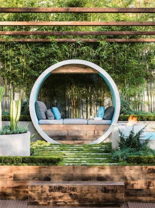 ديكور حديقة Zen ، درج أخضر ، مقعد خشبي مع وسائد مقاعد رمادية ووسائد زخرفية باللونين الرمادي والأزرق ، جدار من الخيزران ، عريشة خشبية