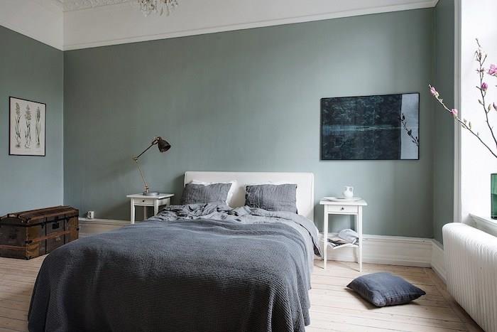 zelené steny v dizajnérskej spálni pre dospelých, parkety zo svetlého dreva, sivá posteľná bielizeň, vinobranie, komoda, škandinávska spálňa