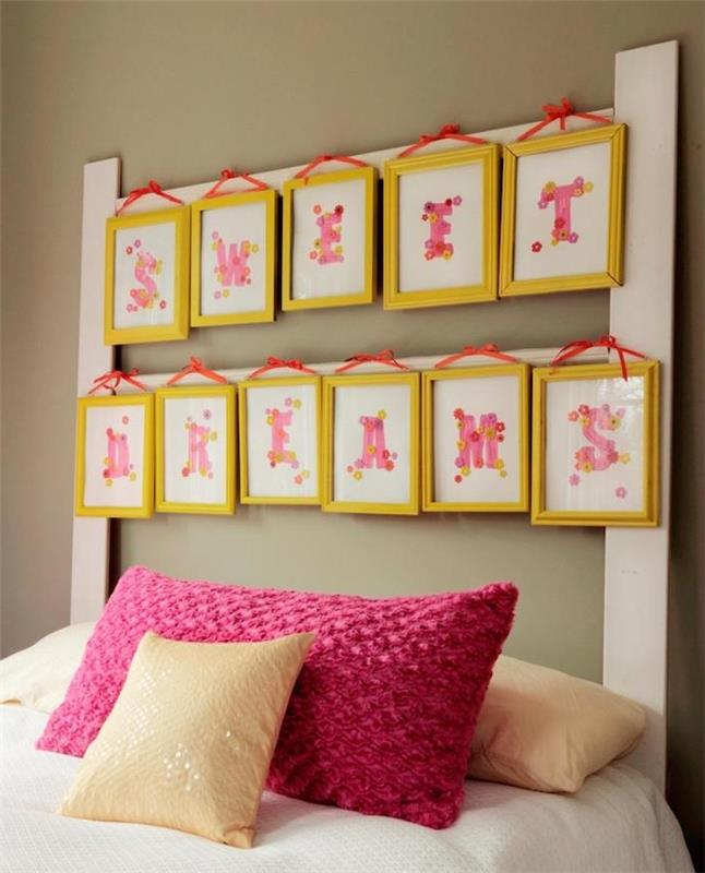 exempel på en gör-det-själv-sänggavel, gula ramar med rosa bokstäver, vita sängkläder, beige och lila kuddar