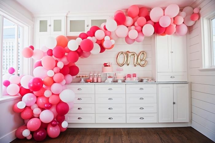 en båge av ballonger i nyanser av rosa och brevballonger för 1 år gammal födelsedagsdekoration