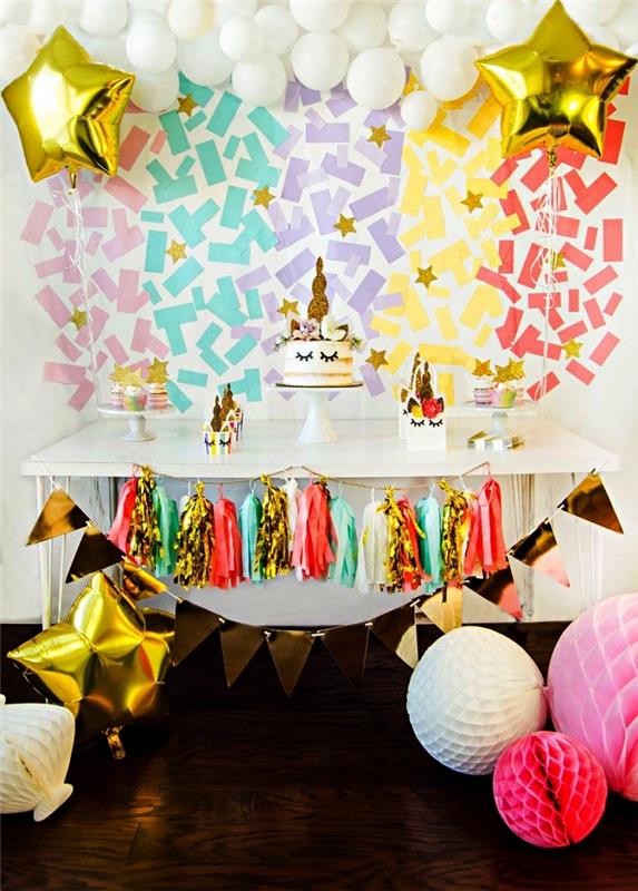 Deco -idé om enhörningens födelsedagstema, bakgrund av regnbågskonfetti och krans av vita ballonger för dekoration av gourmetbuffén