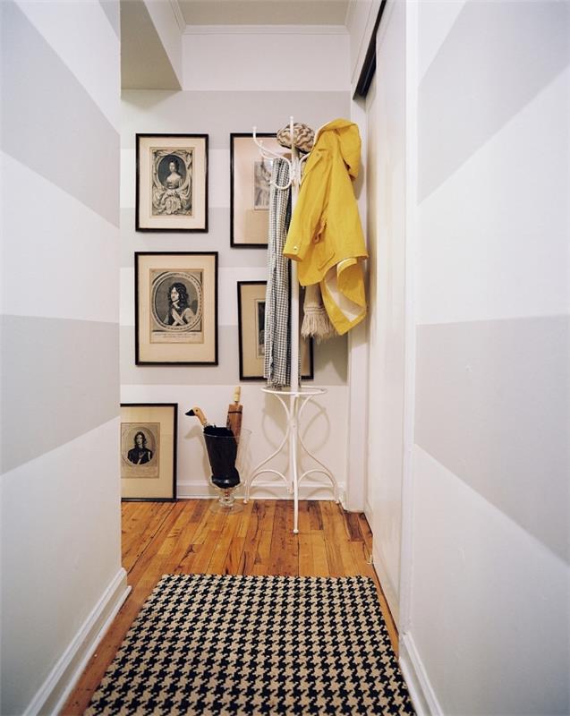grafisk korridordekoration med målade väggar med ljusgrå och vita horisontella färgband, liten korridor i skandinavisk stil i vitt, grått och inslag av svart