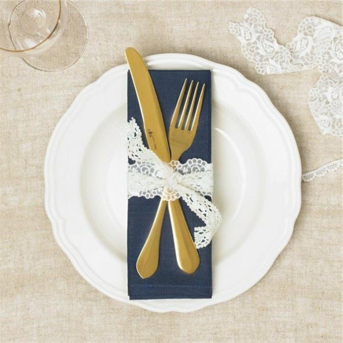 bröllopsdekorationsidé, en marinblå servett, tätt bestick med vitt spetsband, bordsdekoration