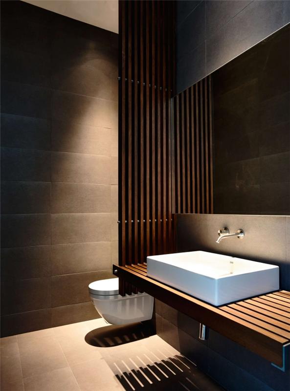 Japonsky inšpirovaný dekor v tmavých farbách a dreve, súčasný dizajn kúpeľne so sivými stenami s umývadlom a toaletnou misou v bielej farbe