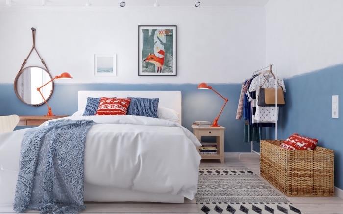 spálňa v škandinávskom dome, škandinávsky biely posteľný nábytok, biela, modrá a červená posteľná bielizeň, dekorácia steny na modro a bielo, okrúhle zrkadlo, čiernobiely koberec, dekorácia steny kresliaca líšku