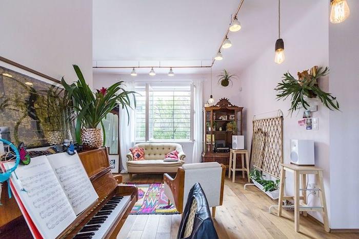 nöjesområde med piano öppet till vardagsrum med vitvit soffa, ljus träparkett, originalbelysningsspänningar, exotiska antika möbler