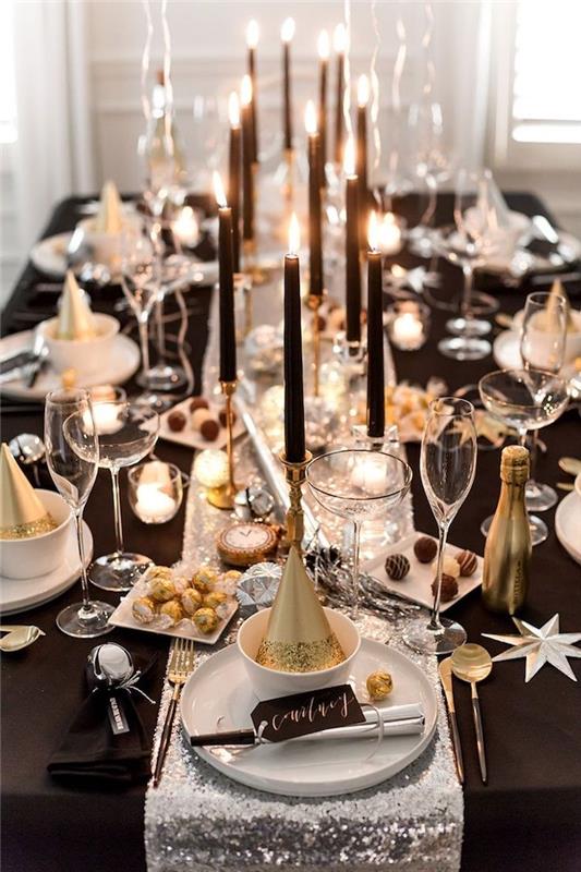 bord dekorerat med svart bordsduk och silver bordsskiva, svarta ljus på guldljus, elegant svart, vitt och guld deco