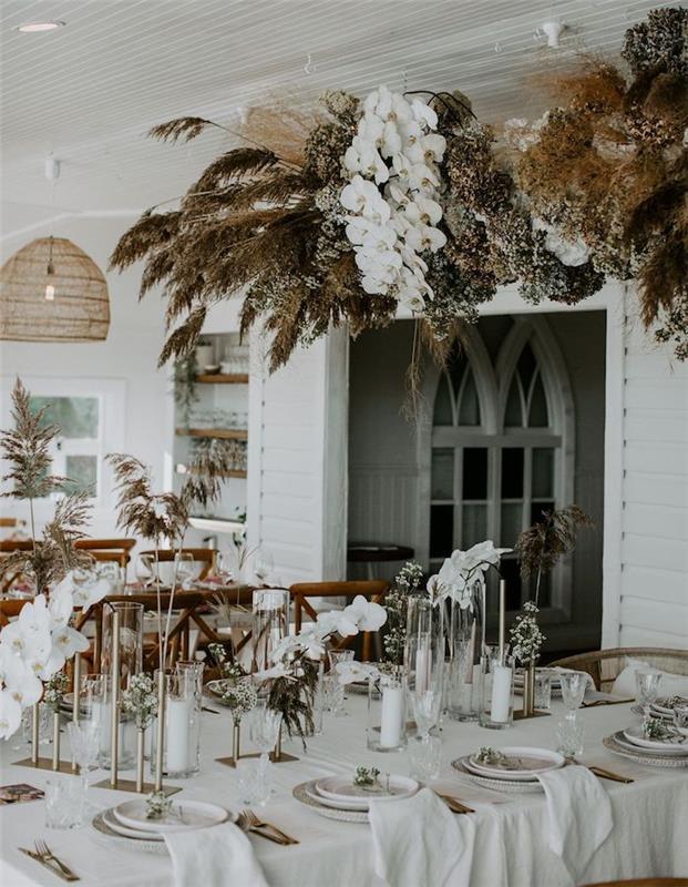 veniec bielej, hnedej a tmavozelenej vegetácie. dekorácie bieleho svadobného stola s bielymi kvetmi, stredomorská svadobná výzdoba