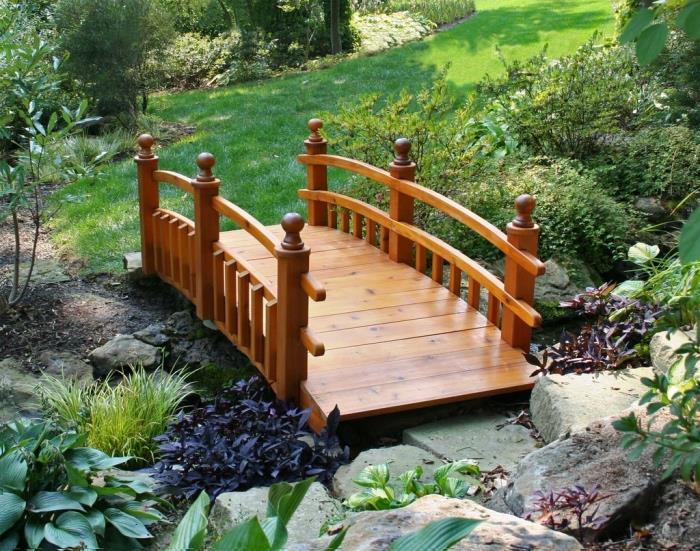 عنصر أساسي في حديقة زين ، جسر خشبي صغير ، شجيرات ، عشب وحجارة ، نباتات خضراء