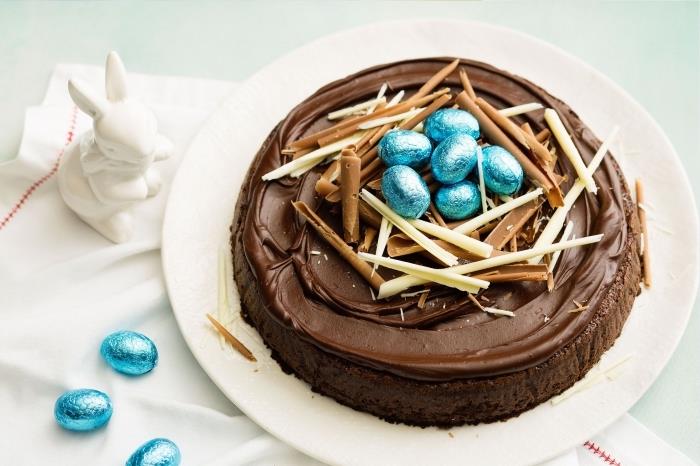 Enkel choklad påsktårta på en bas av mjuk kakaosvampkaka toppad med chokladsmörkräm och dekorerad med mjölkchokladspån, fågelbo -stil