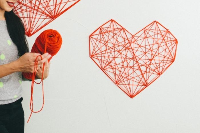 spänt trådbord DIY -mönster i form av ett stort hjärta i röd tråd och origami -design som väggdekoration