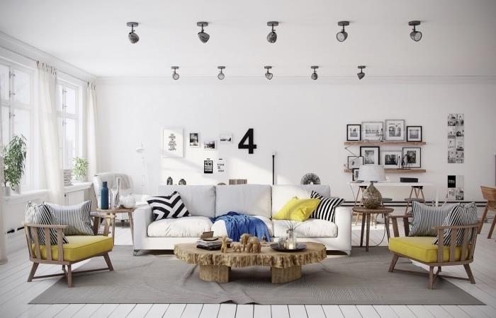 Škandinávska výzdoba obývačky, sivý koberec, sivobiela pohovka, drevené stoličky so žltými podsedákmi, rustikálny drevený stôl, nástenná výzdoba kresieb a fotografií v čiernobielom prevedení