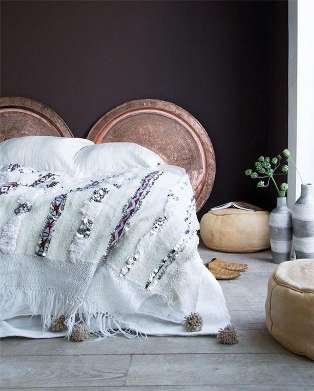 benvita sängkläder, svart vägg dekorerad med trä stockar, grå parkett, beige ottomaner, vit och grå vas, orientalisk sänggavel sovrum inredning