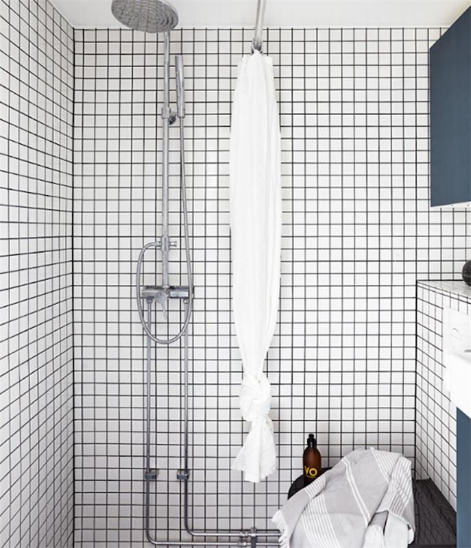 malý dizajnový model kúpeľne s bielymi obkladmi, striebornou sprchou a modrými úložnými jednotkami