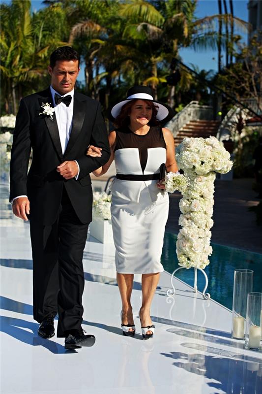peplumklänning i vitt och svart med svart tyllinsats åtföljt av en matchande bröllopshatt, 50 års bröllopsklänning för brudens mamma