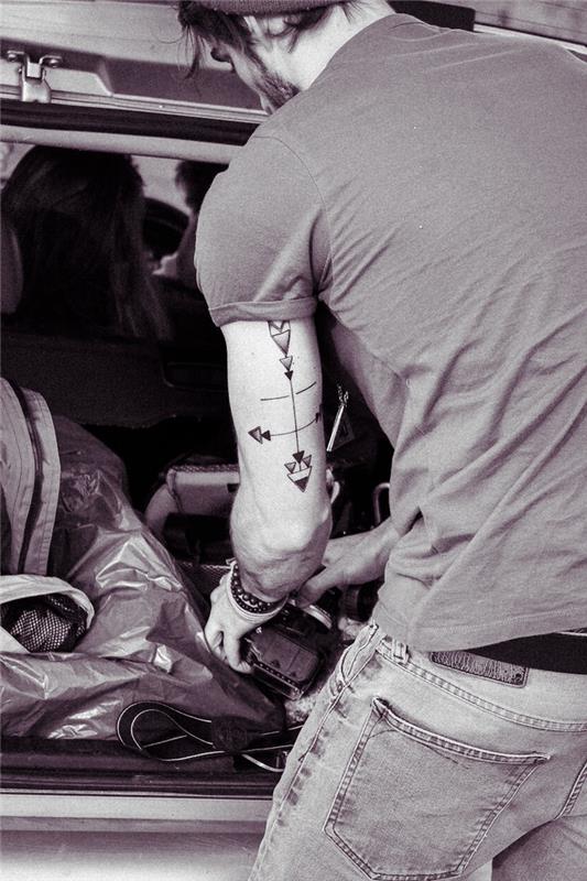 tetovanie ramena muža predstavujúce štyri geometrické šípky symbolizujúce štyri smery