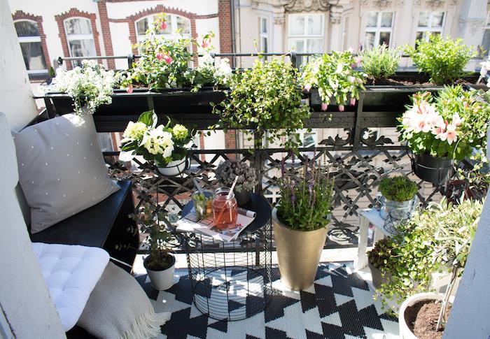 liten balkong, liten terrassarrangemang, trästol, grå kuddar och filt, svartvitt matta, blomkrukor, gröna växter, bord i uppfällt skräp
