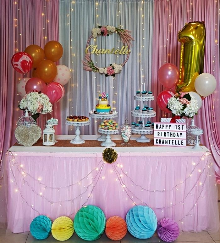 flickaktigt födelsedagsdekoration i rosa och guld, sött 1 års födelsedagsbord, dekorerat med ballonger, led -kransar, bikakebollar och en ganska personlig blommakrona