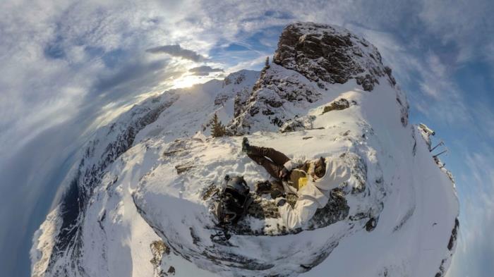 himmelskt landskap, snöigt berg, utsikt uppifrån, virveleffekt, blå himmel med vita moln, stenig topp