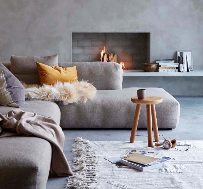 enkelhet och mjukhet i detta gråa vardagsrum med betongeffektväggar med inbyggd öppen spis och en stor mysig soffa