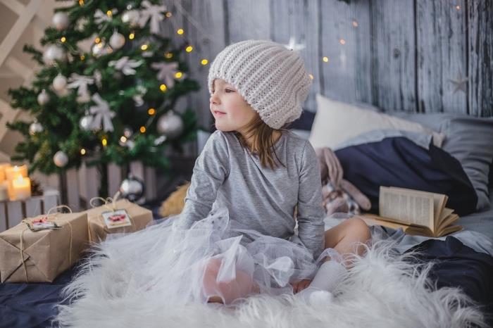 nápad na počítačovú tapetu na útulnej vianočnej téme, fotografia dieťaťa obklopeného vianočnými darčekmi pred ozdobeným stromčekom