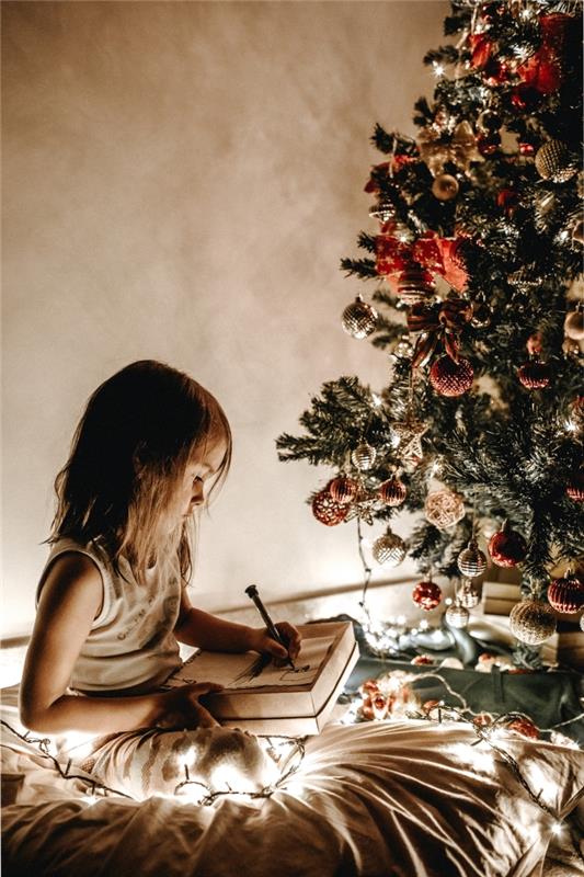 nápad, ako ozdobiť stromček ozdobami v červenej a zlatej farbe, fotografia dievčatka, ktoré píše svoj list Ježiškovi