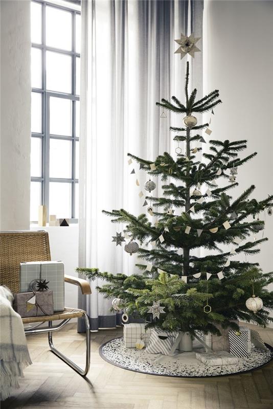 minimalistisk julgransdekoration i ett vitt rum och skandinaviskt trä, julgran dekorerad med metalliska prydnader