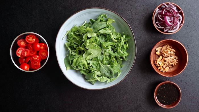 ingrediencie na výrobu jednoduchého domáceho šalátu z rukoly špenát cherry paradajky vlašské orechy červená cibuľa a jednoduchá vinaigretta