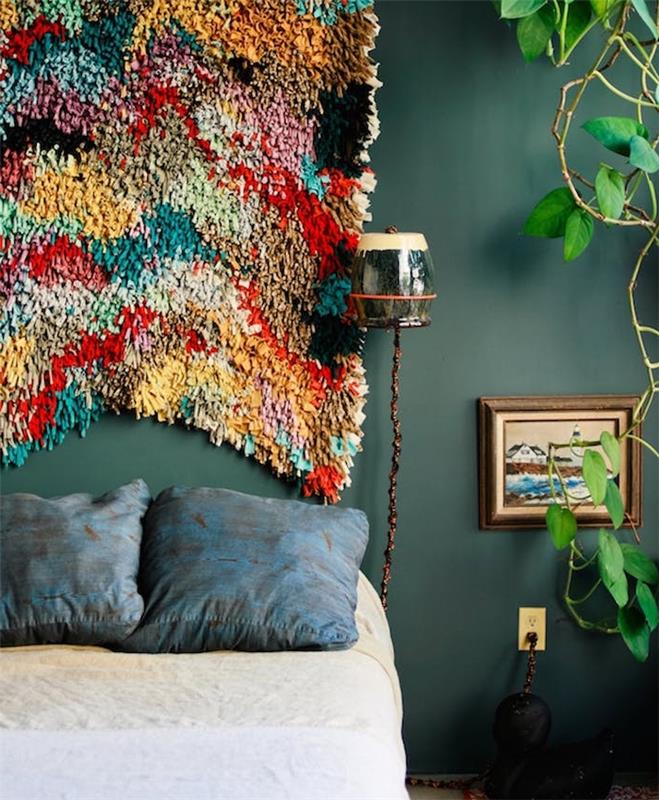 exempel på färgglada tyggavel, mörkgrågrön vägg, beige och vita sängkläder och blå dekorativa kuddar, grön växt