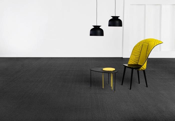 minimalistisk design med belysningshänglampor i matt svart och en svart och gul stol, färg som blandas med grått