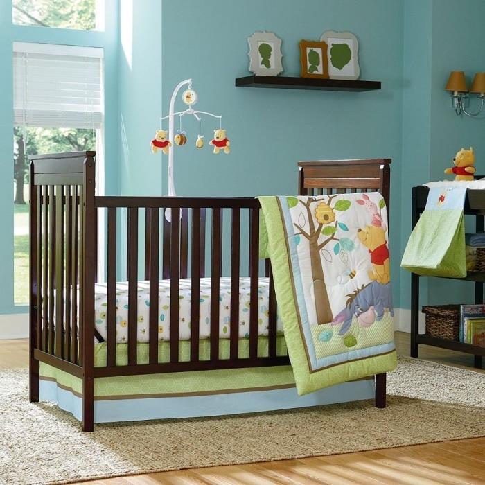 Rozloženie detskej izby pre novorodencov so svetlo modrými stenami a svetlou drevenou podlahou, tematický dizajn s detským mobilom Medvedík Pú