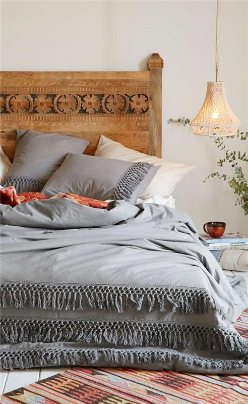 bohemiskt sovrum, sänggavel i trä, hängande lampa, grått sängset, grå kuddar, etnisk matta