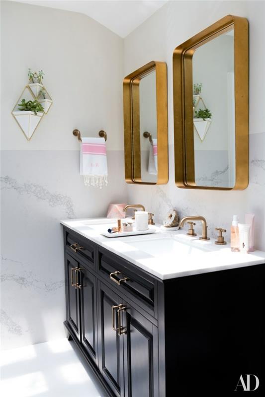 čiernobiela kúpeľňa, toaletný stolík z tmavého dreva, dve zrkadlá s kovovým rámom a zlaté kovové batérie
