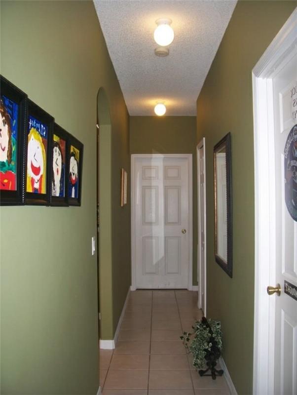 جدران باللون الأخضر الكاكي ، وسقف أبيض ، وبلاط أرضي باللون البيج الفاتح ، داخل ممر بثلاثة أبواب بيضاء ، وأفكار ممرات صغيرة ، ومرآة مؤطرة وأربعة رسومات للأطفال على الجدران