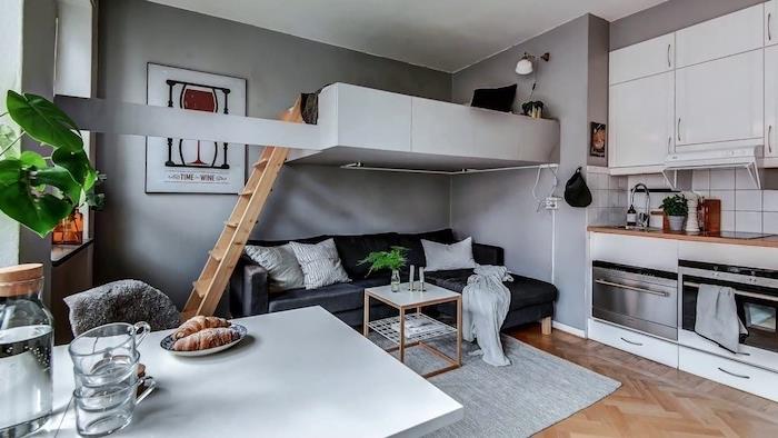 grå soffa och vardagsrumsbord under vit hög säng, grå väggar och pentry för vit studio, vitt matbord