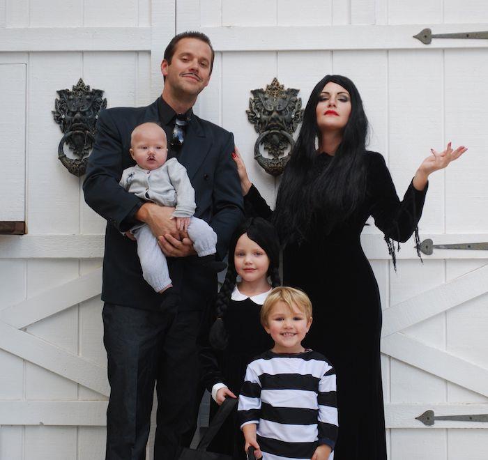 addams rodinný nápad halloween kostým pred bielymi dverami čierne kostýmy dlhé vrkoče