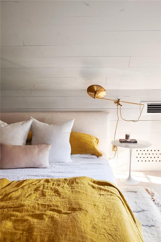 exempel vitt sovrum under sluttning, stor sängmodell med beige sänggavel och senapsfärgat täcke