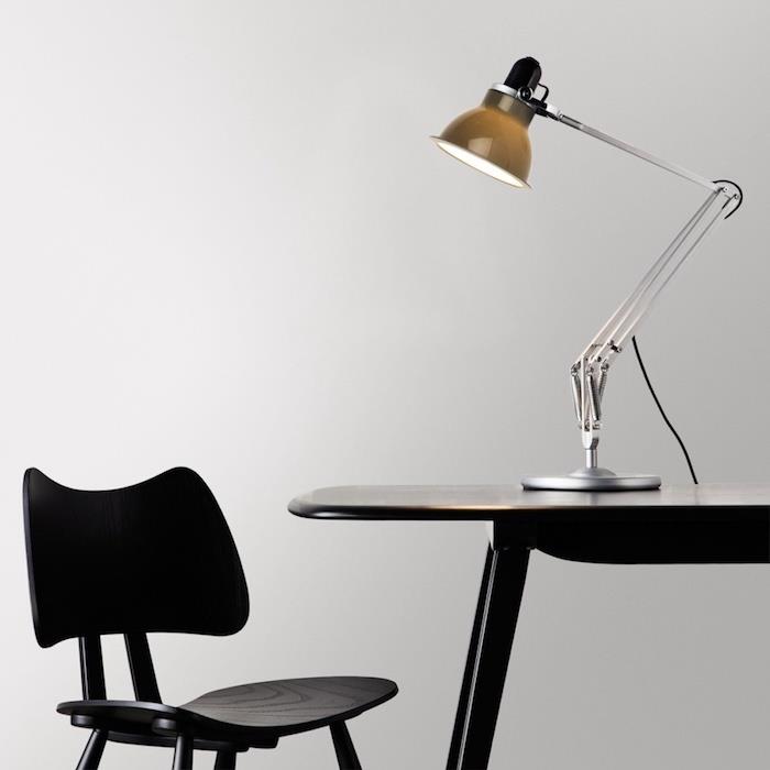 تحسين الأداء الفكري ومصباح المصمم وكرسي وطاولة سوداء ومساحة عمل بسيطة وجمالية