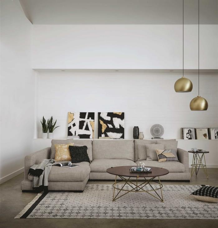 moderný model obývačky s bielymi stenami zariadený rohovou sedačkou a doplnkami v zlatých povrchových úpravách a etnických vzoroch